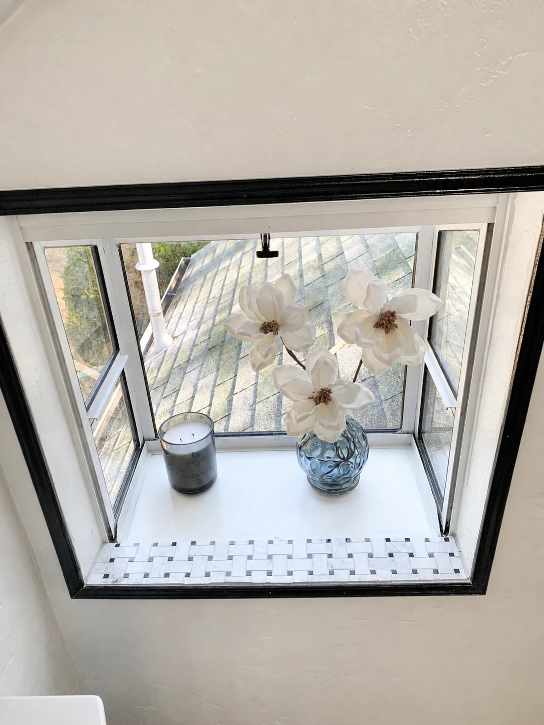 Projecting attic bathroom garden window with a flower and candle on its tiled ledge