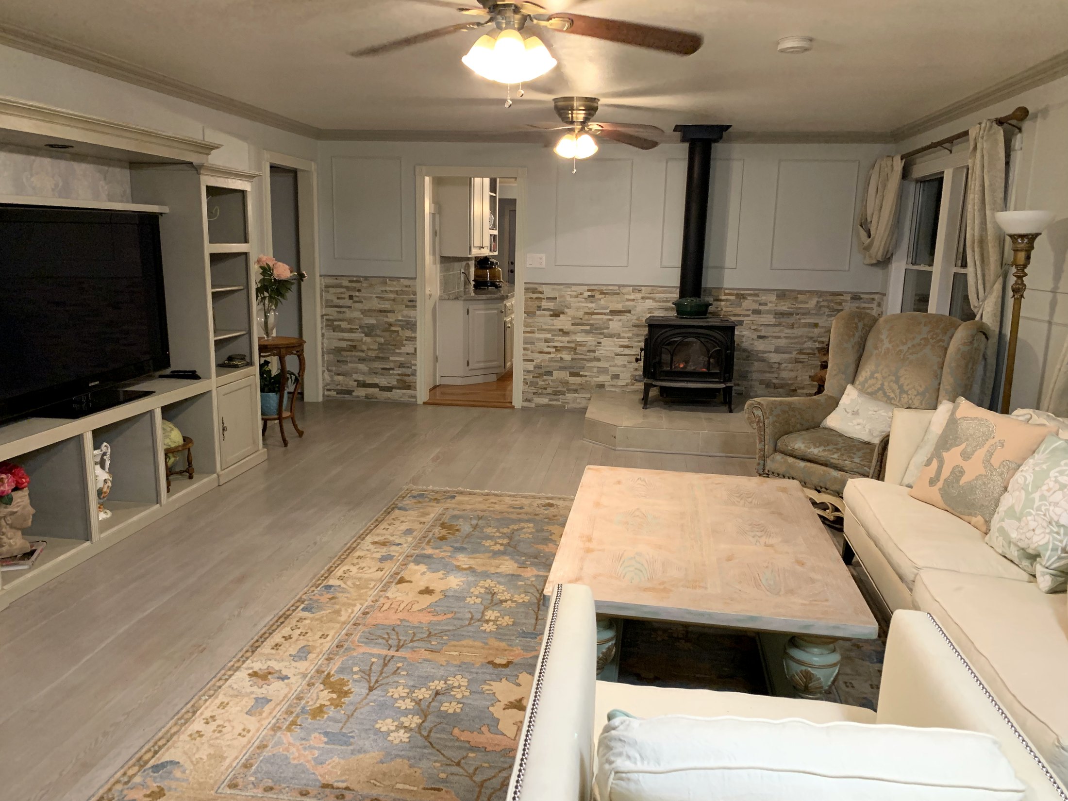 Finished California farmhouse living room with paneled walls, Jøtul stove, and transformed built-in